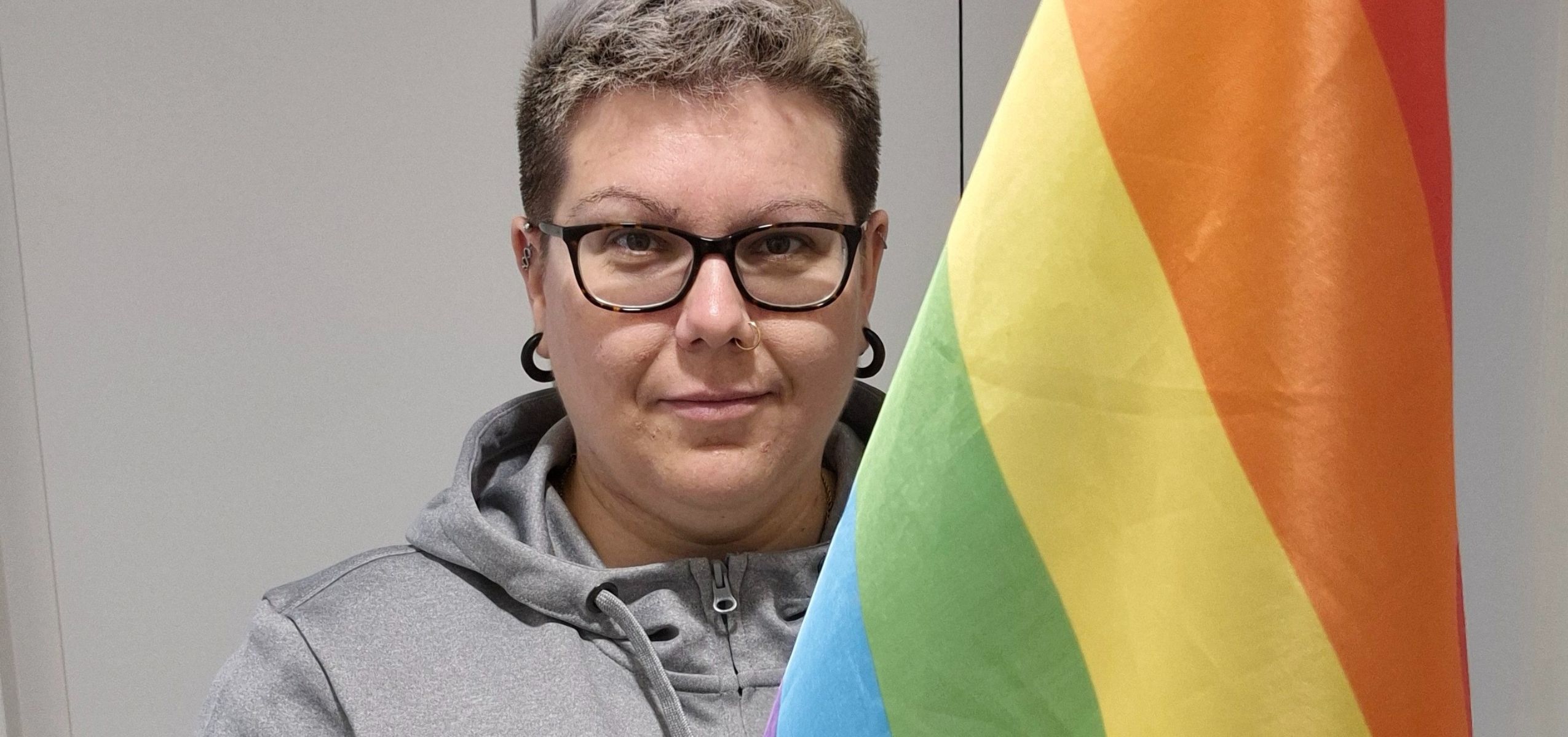 V-S FinFamin puheenjohtaja Alti Forth pitelee sateenkaaren väreissä olevaa lippua.