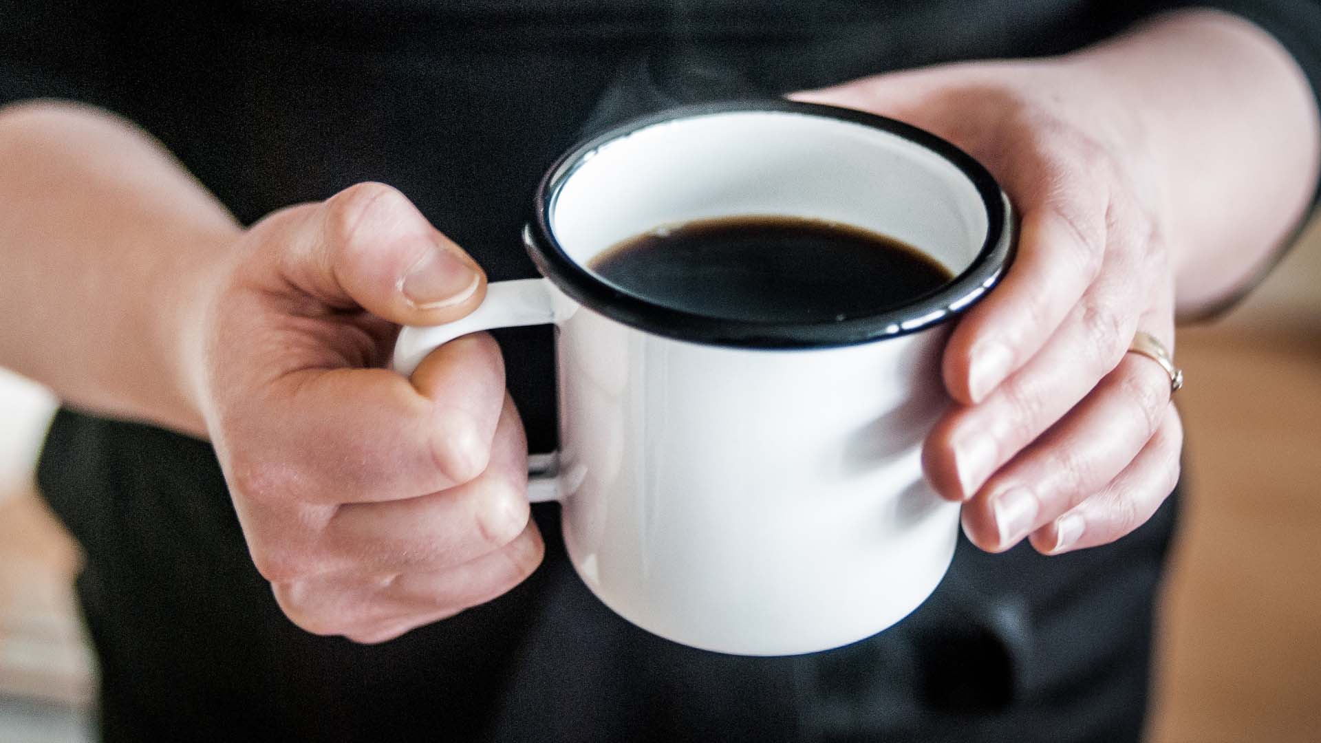 Henkilö pitelee käsissään kahvikuppia