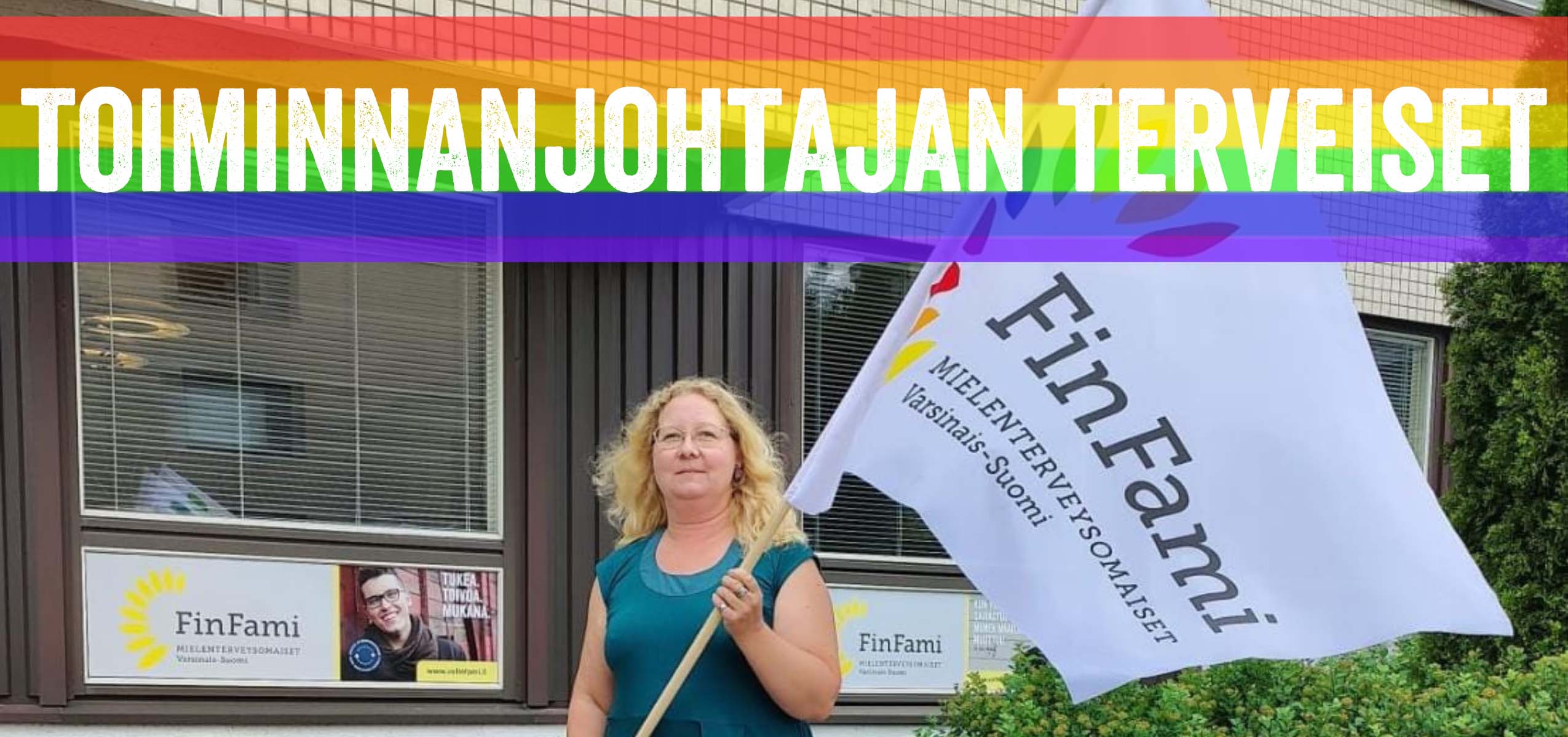 V-S FinFamin toiminnanjohtaja Milla Roos sateenkaarivärityksellinen V-S FInFamin lippu kädessä. Kuvan ylälaidassa teksti "Toiminnanjohtajan terveiset".